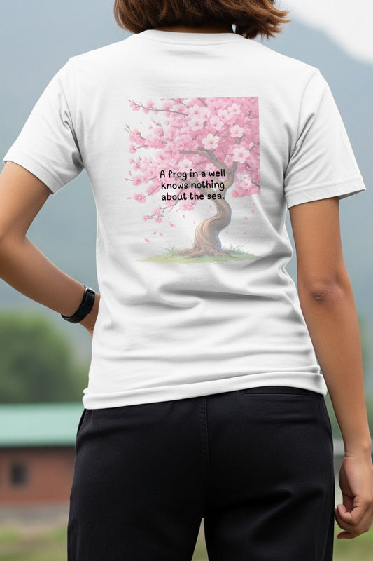 A woman modeling the back of ZUPPI's "A frog in a well knows nothing about the sea" white T-shirt, showing the full graphic and text