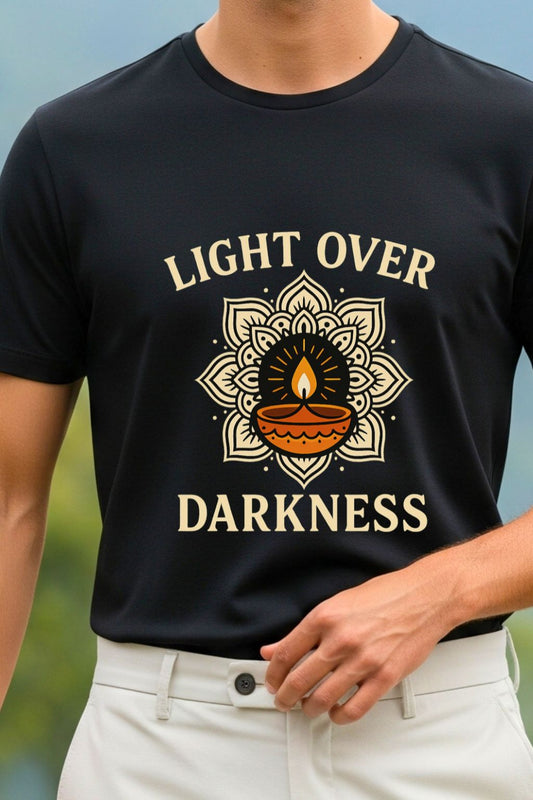 Close-up of a black graphic t-shirt featuring a stylized 'Light Over Darkness' design. The detailed print includes an intricate mandala pattern and a lit candle, perfect for inspirational or Diwali-themed apparel.