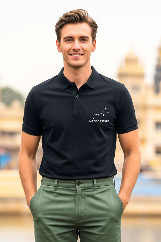 A handsome man stands with his hands in his pockets, confidently modeling a black ZUPPI 'Made of Stars' polo t-shirt