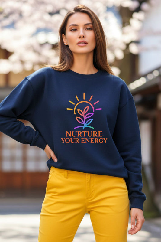 Woman wearing a navy blue oversized sweatshirt with 'Nurture Your Energy' text and colorful design outdoors.