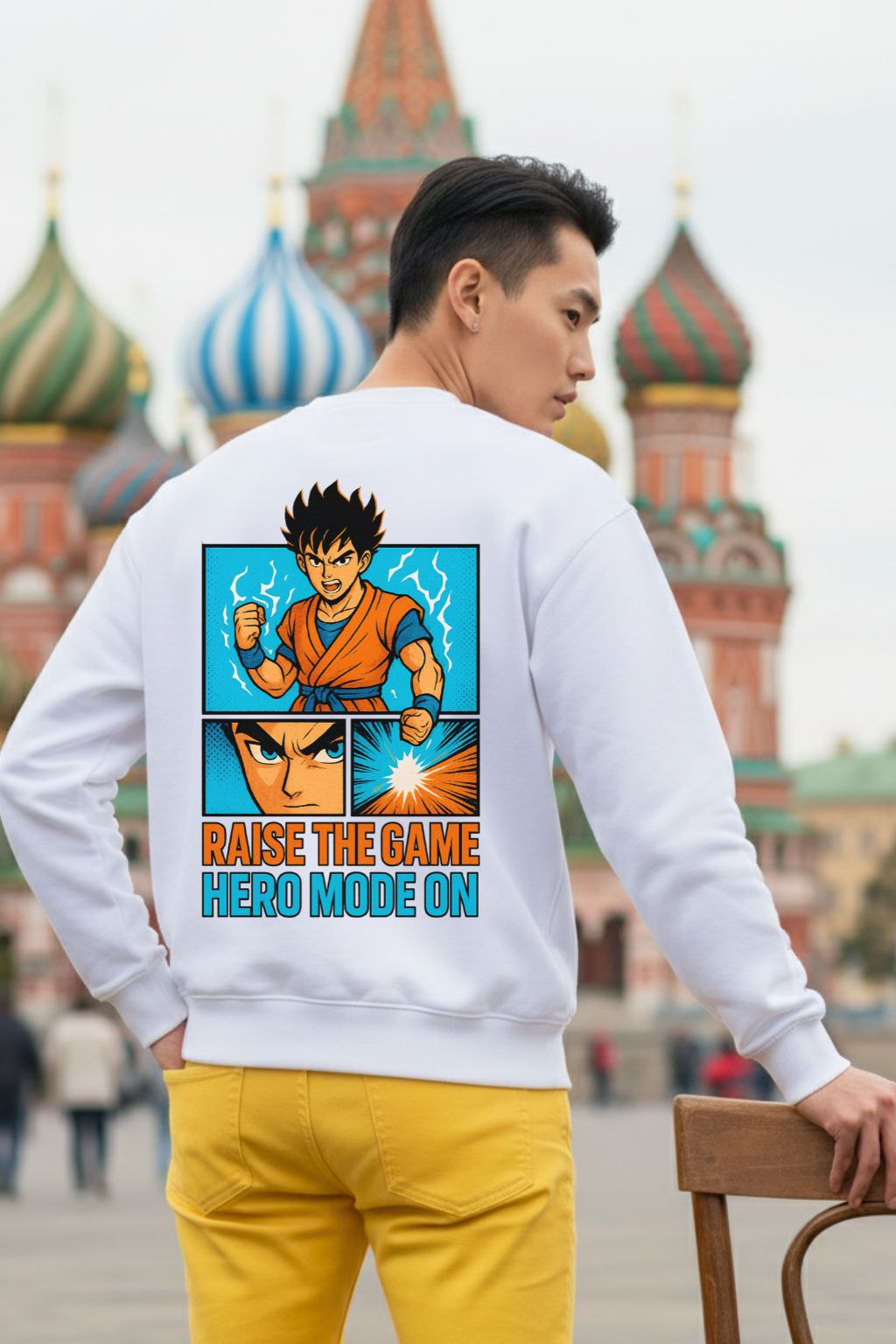 Back view of a man wearing a white oversized sweatshirt with a colorful graphic and text, standing in front of a blurred cityscape.