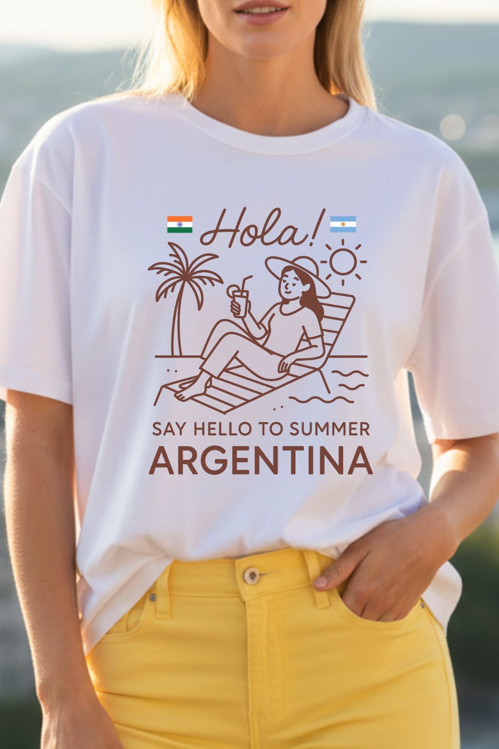 Close up of a woman wearing a white t-shirt with a summer-themed design and text, standing by a body of water.