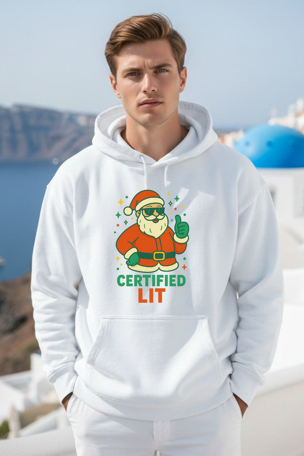 Man wearing a white oversized hoodie with a Santa Claus graphic and text, standing in a scenic location.