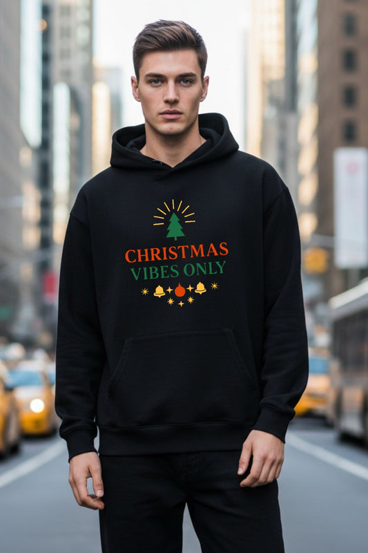 Man wearing a black hoodie with 'Christmas Vibes Only' text on a city street.