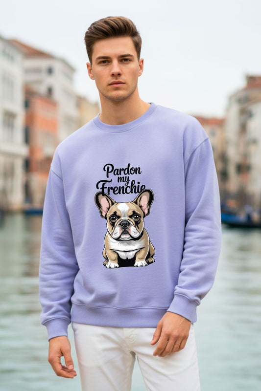 Man wearing a lavender oversized sweatshirt with a dog graphic and text, standing by a waterfront.