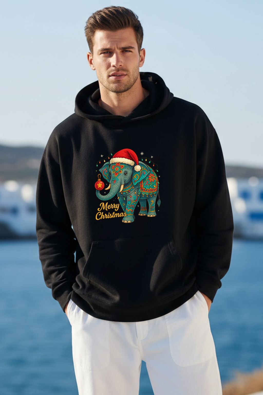 Man wearing a black hoodie with a Christmas-themed elephant design by the water.