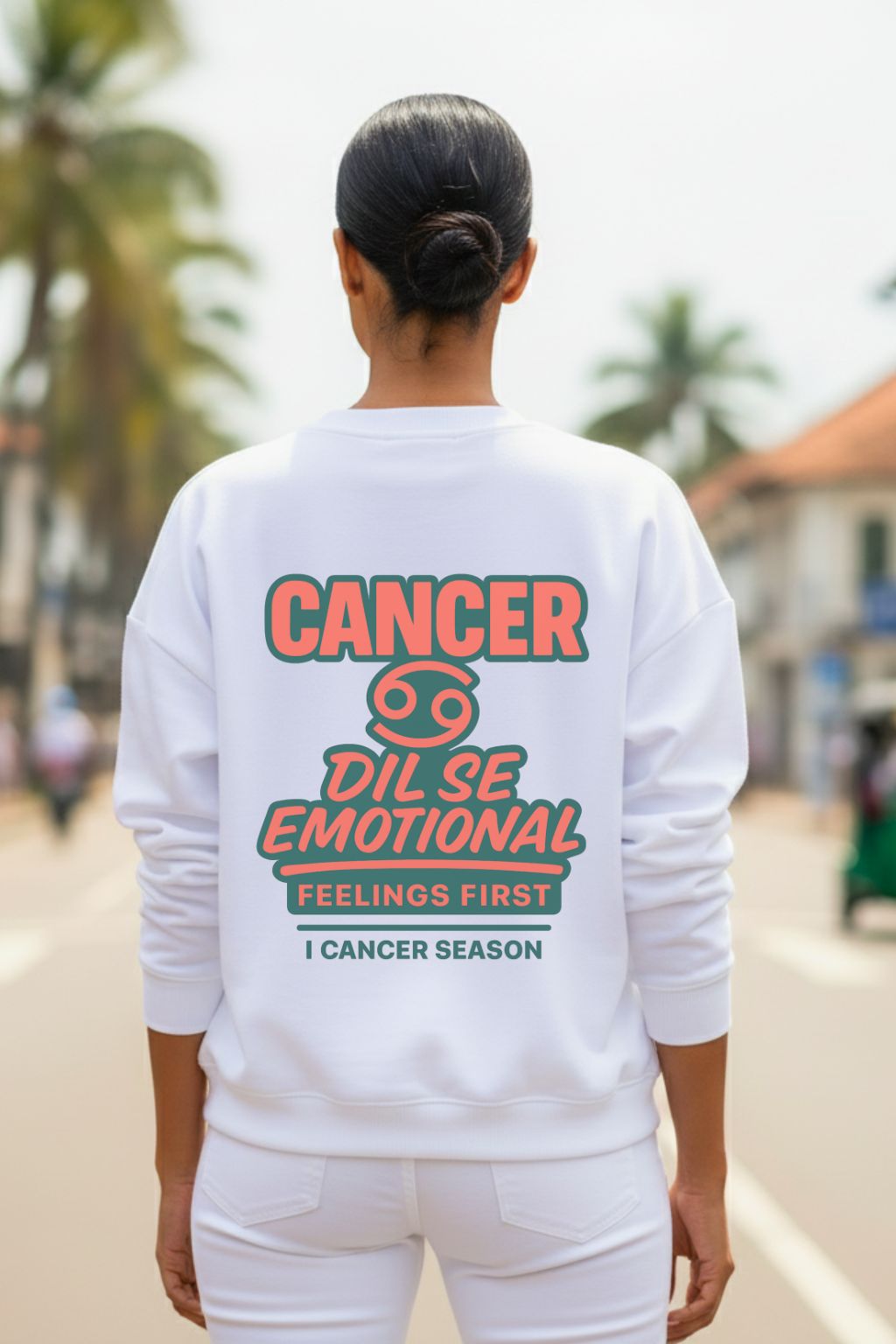 Woman wearing a white oversized  sweatshirt with text, related to cancer zodiac sign,  on the back in an outdoor setting