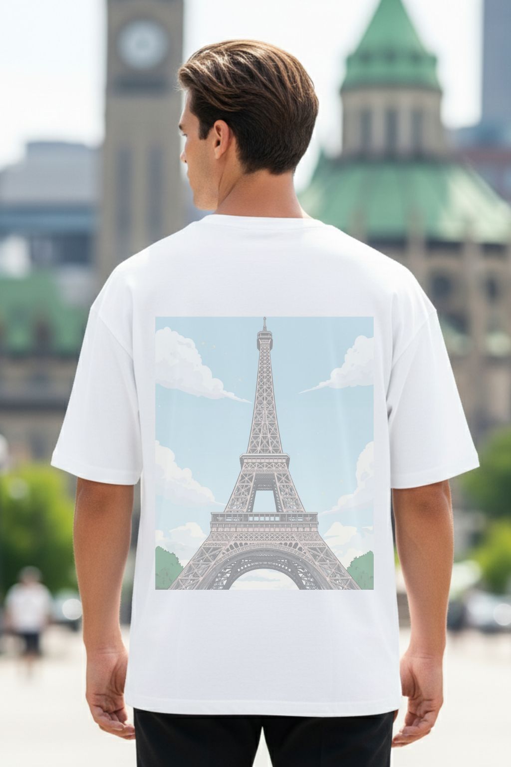 Man wearing a white t-shirt with the Eiffel Tower graphic on the back, and a French quote in the front, standing in an urban setting.