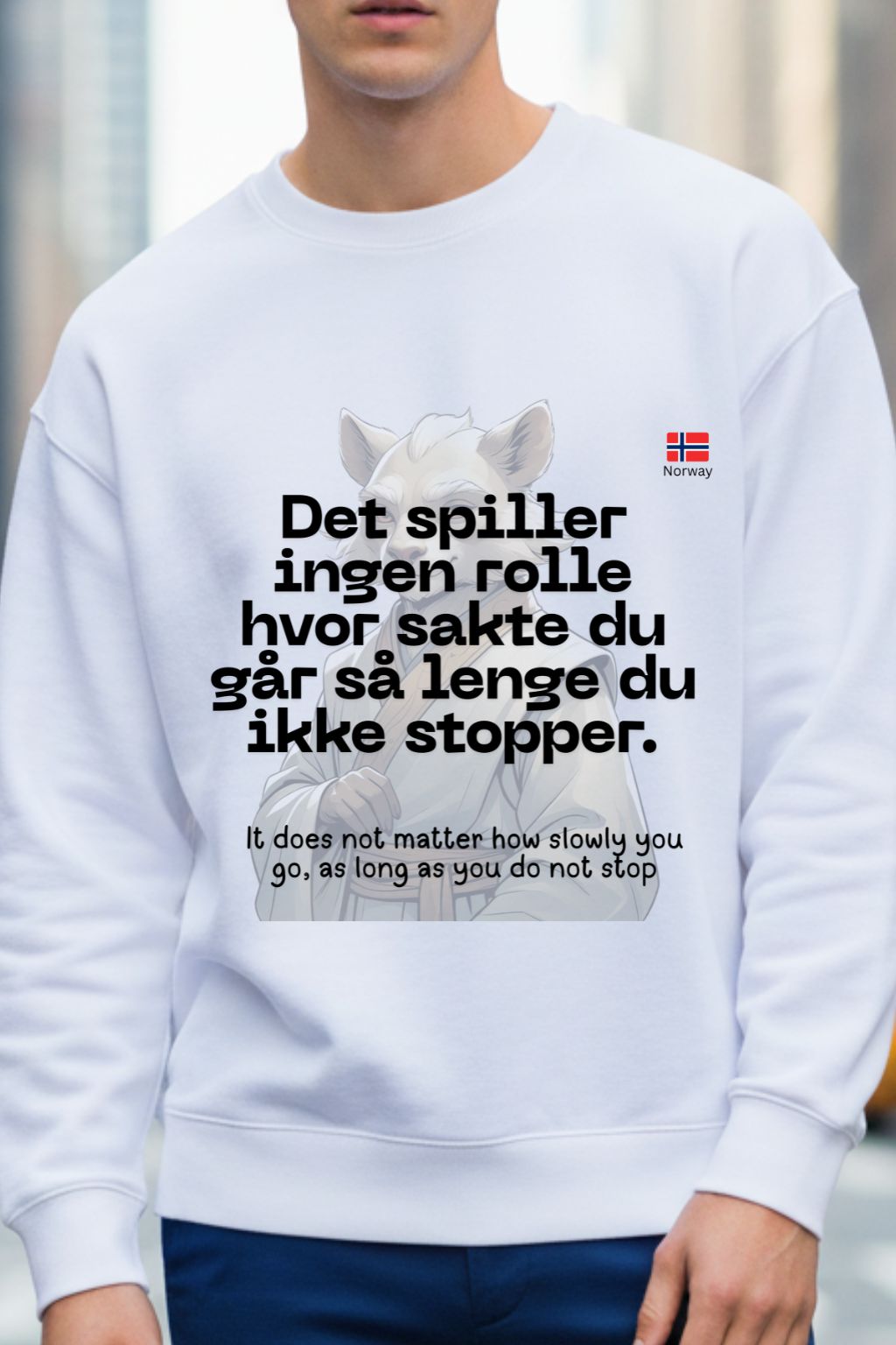 Man wearing a white sweatshirt with text and a logo, standing against a blurred background.