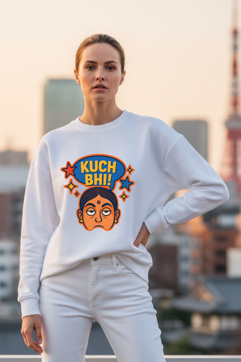 Woman wearing a white sweatshirt with a colorful graphic design of "Kuch Bhi" in an urban setting