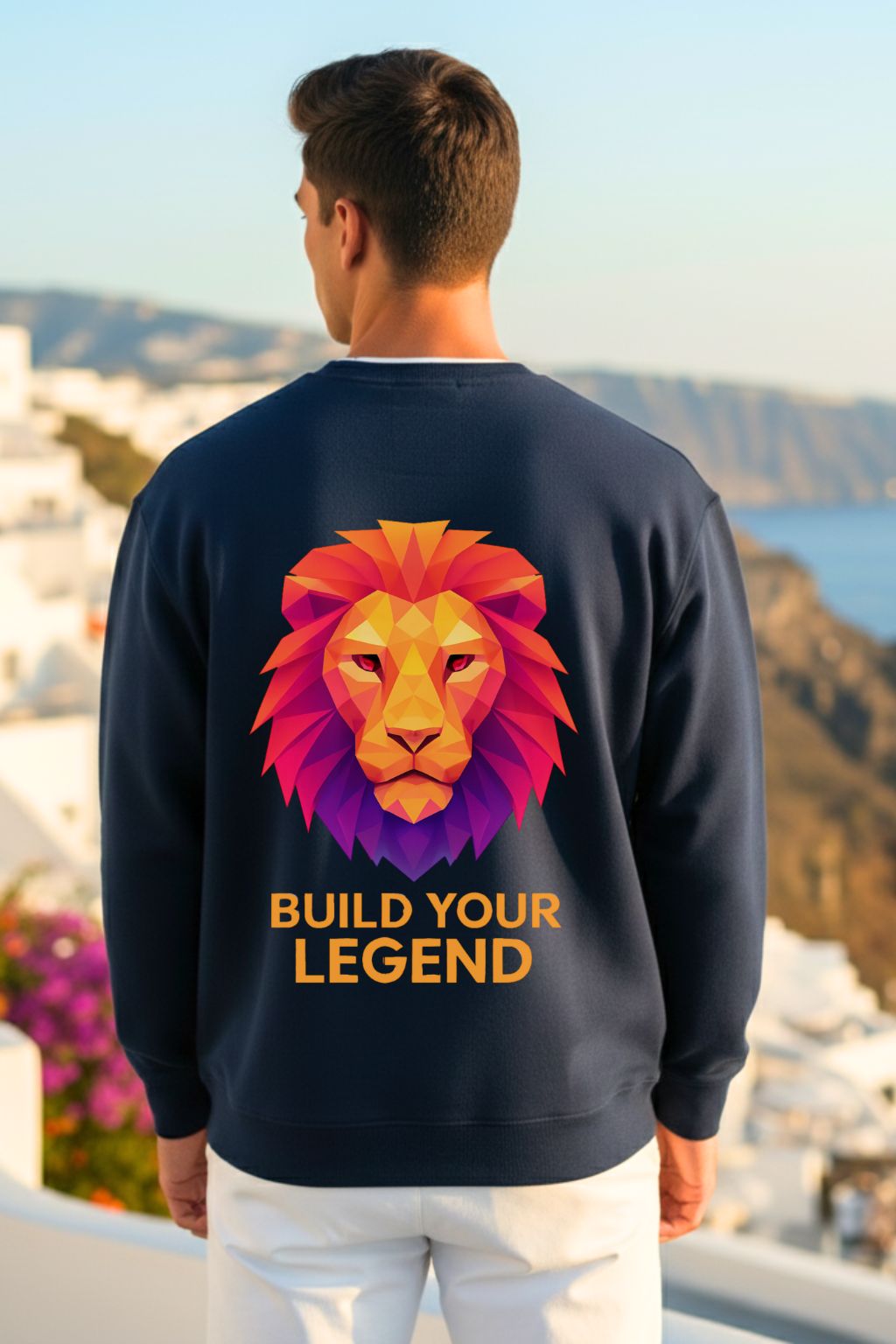 back view of a man wearing a navy oversized sweatshirt with a colorful lion graphic and 'Build Your Legend' text, standing against a scenic background.
