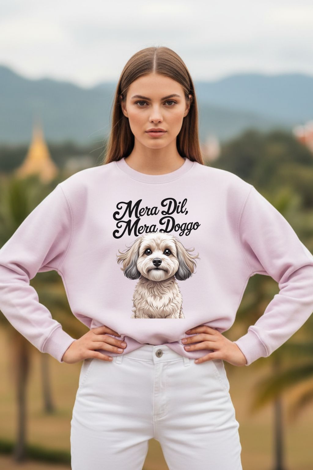Woman wearing a light baby pink oversized sweatshirt with a dog illustration and text in an outdoor setting