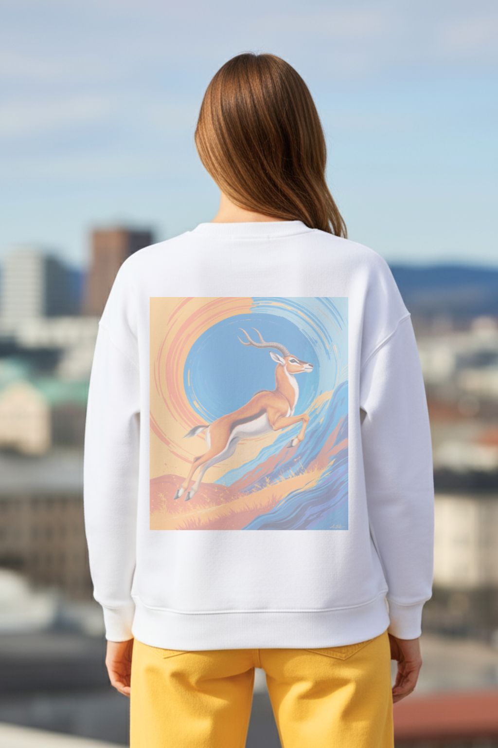 back view of a woman wearing a white oversized sweatshirt with a deer graphic on the back, standing against an urban skyline.