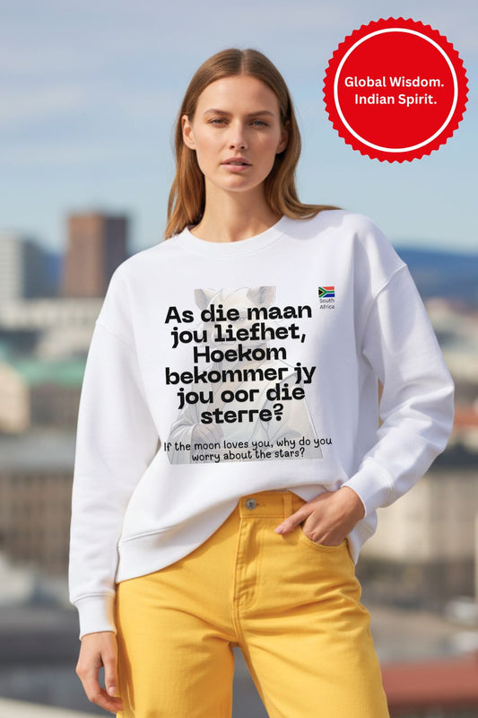 Woman wearing a white oversized sweatshirt with text and a South African flag, standing outdoors with a cityscape in the background.