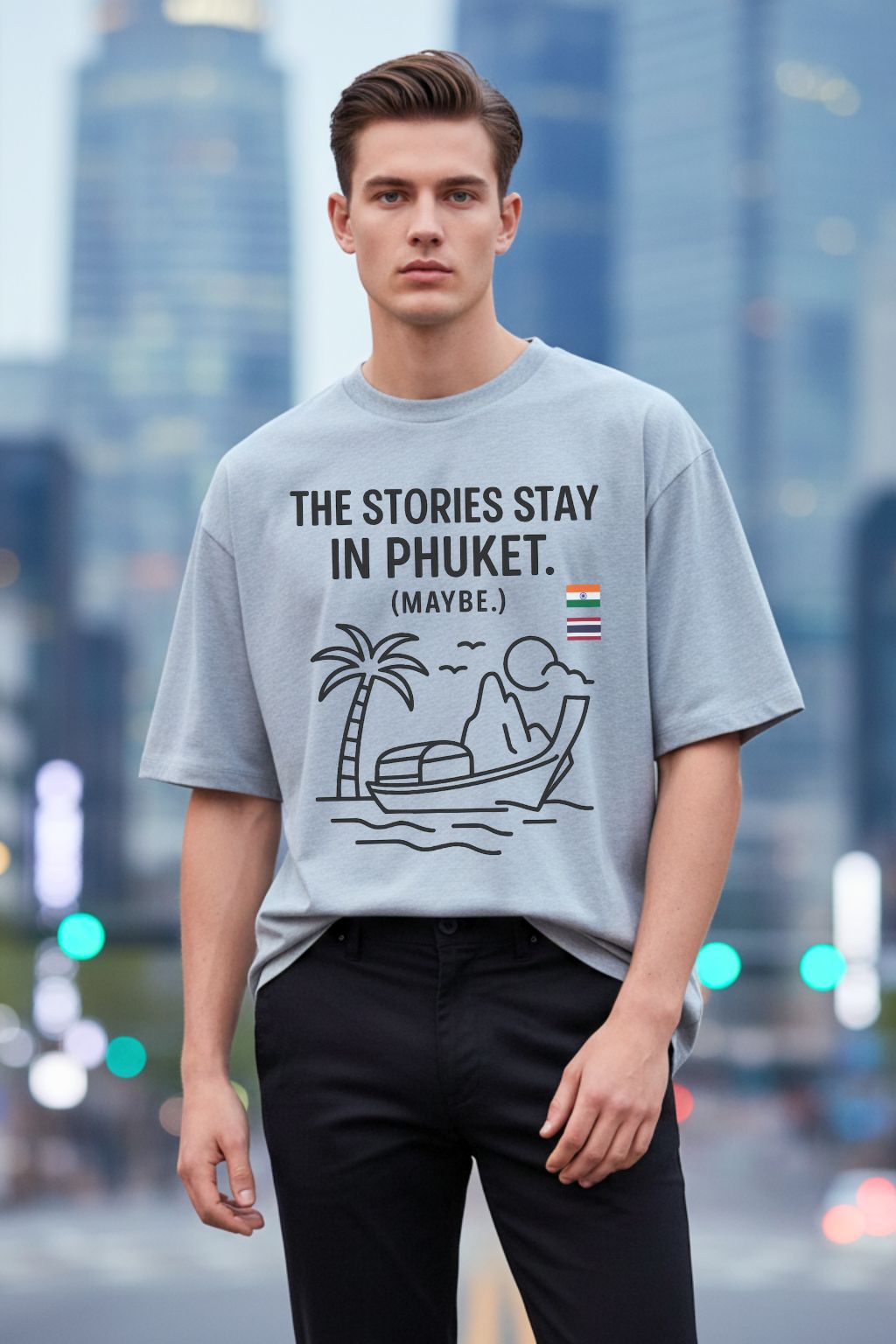 Man wearing a melange gray oversized t-shirt with a graphic design and text, standing in front of a blurred cityscape.