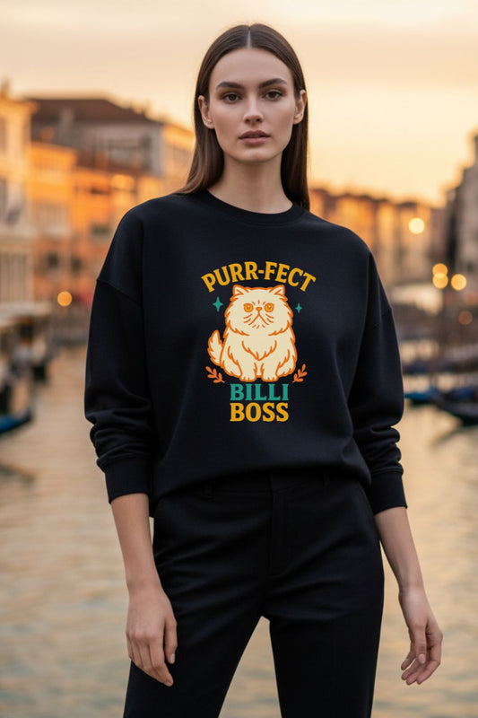 Woman wearing a black sweatshirt with a cat graphic and text, standing by a waterfront at sunset.