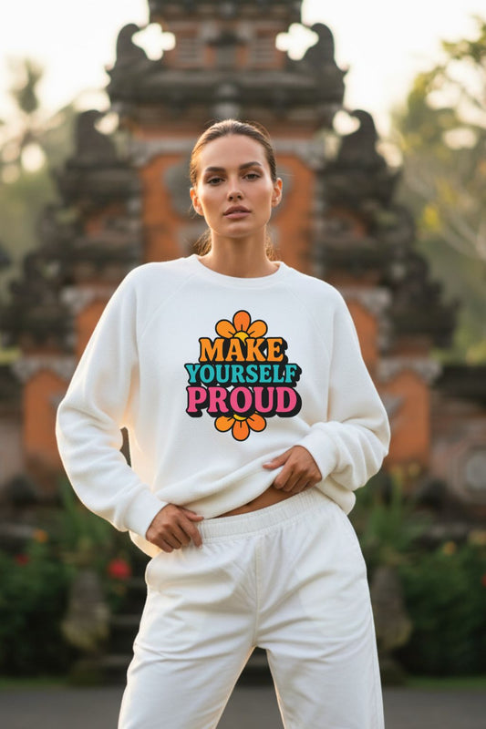 Woman wearing a white oversized sweatshirt with 'MAKE YOURSELF PROUD' text in front of a traditional architectural background.