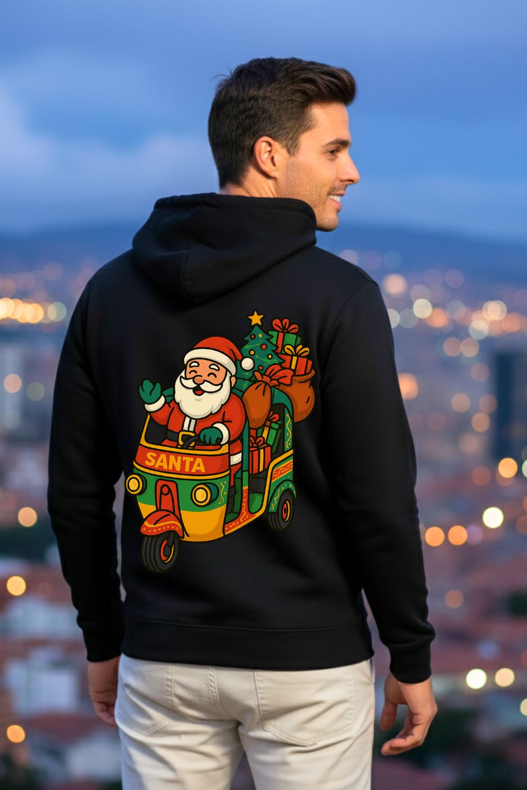 Man wearing a black hoodie with a Santa Claus design on the back, standing against a cityscape at night.