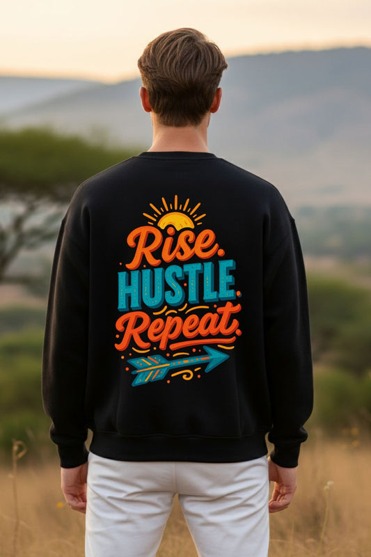 back view of a man wearing a black oversized sweatshirt with 'Rise Hustle Repeat' text, standing in a field.
