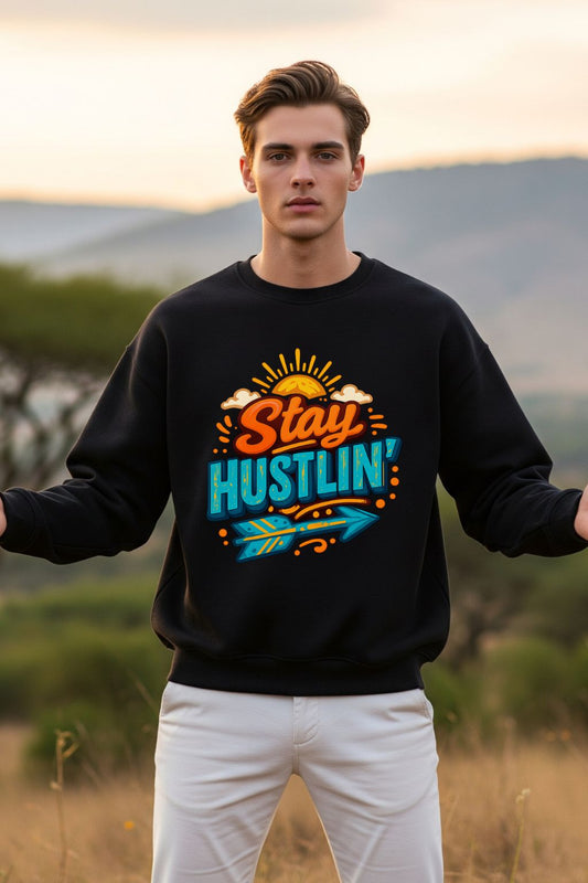 Man wearing a black oversized sweatshirt with 'Stay Hustlin'' text in an outdoor setting