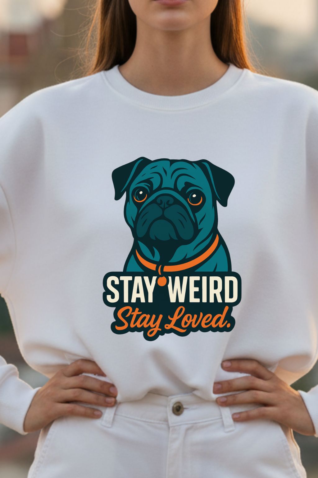Woman wearing a white sweatshirt with a blue pug graphic and text 'Stay Weird Stay Loved'.