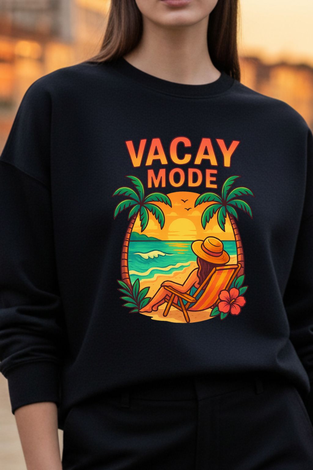 Woman wearing a black sweatshirt with 'Vacay Mode' graphic design featuring palm trees and a beach scene.